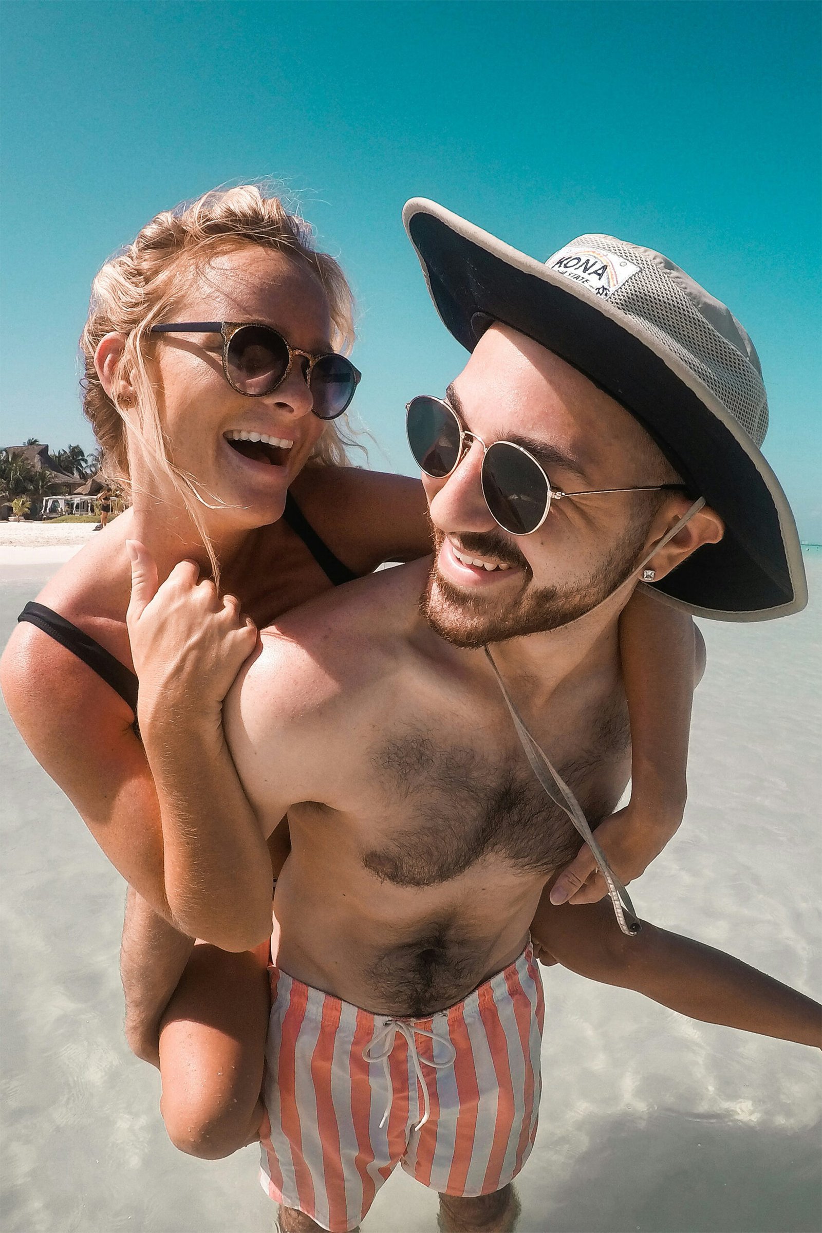 A romantic outdoor lifestyle portrait of a young couple kissing passionately in front of a bright, sunlit natural background.